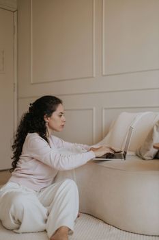 A woman in a relaxed setting using a laptop indoors, showcasing modern home design.