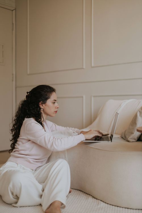 Free A woman in a relaxed setting using a laptop indoors, showcasing modern home design. Stock Photo