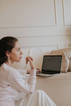 Young woman using a laptop in a comfortable, stylish living room setting.