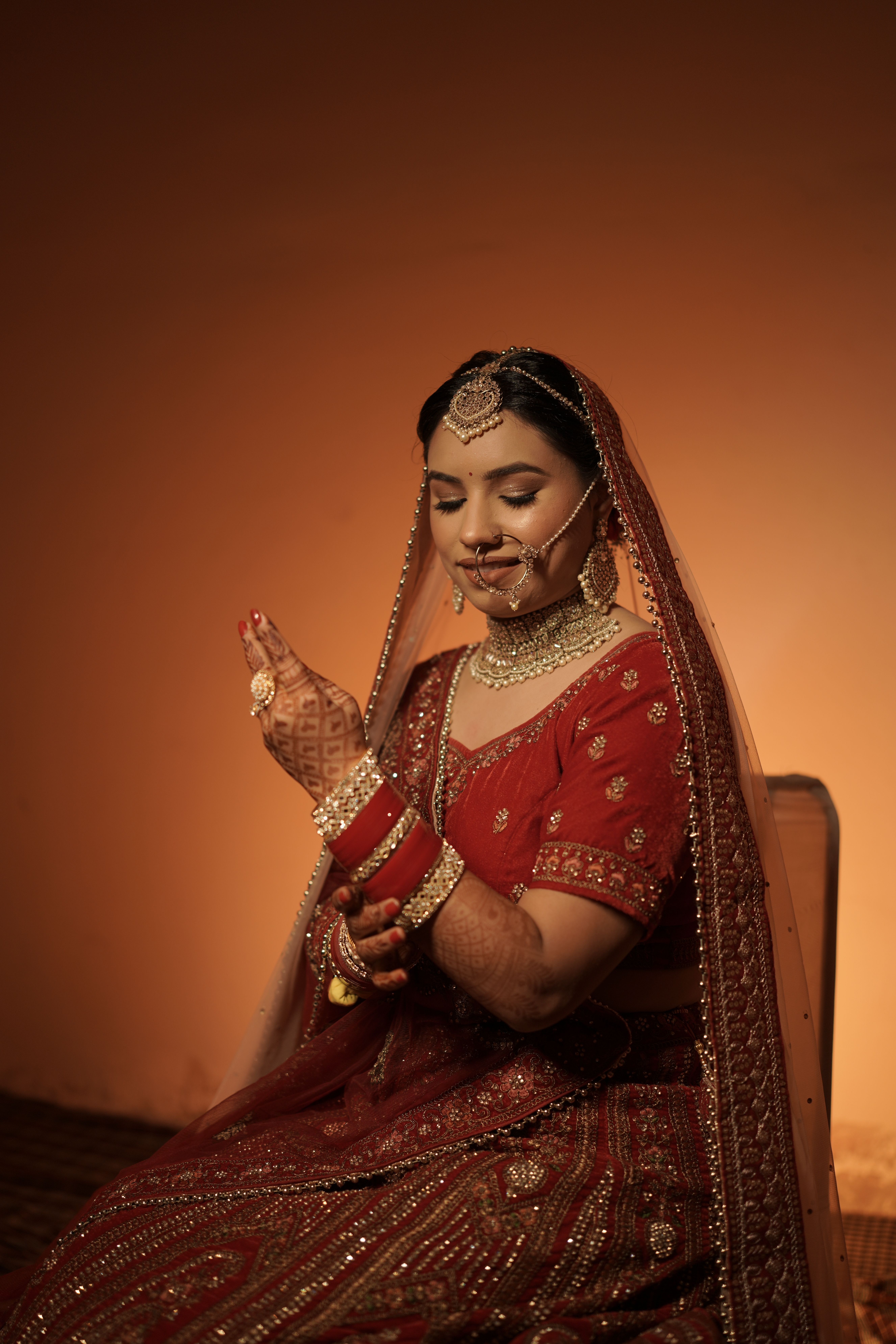 Elegant portrait of a bride in red traditional attire adorned with henna and intricate jewelry.