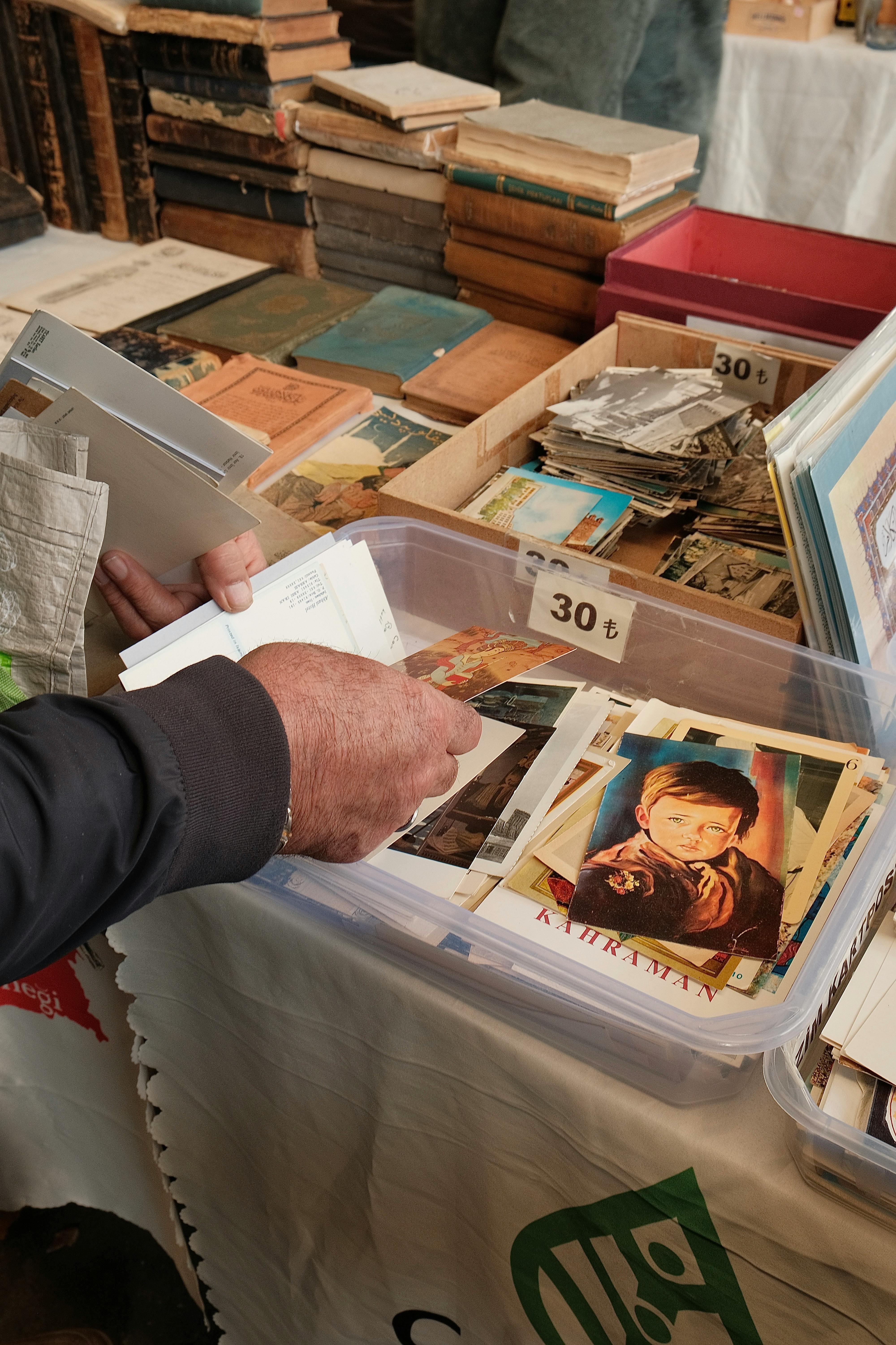 Person browsing vintage photographs at an outdoor market in Ankara, Türkiye.
