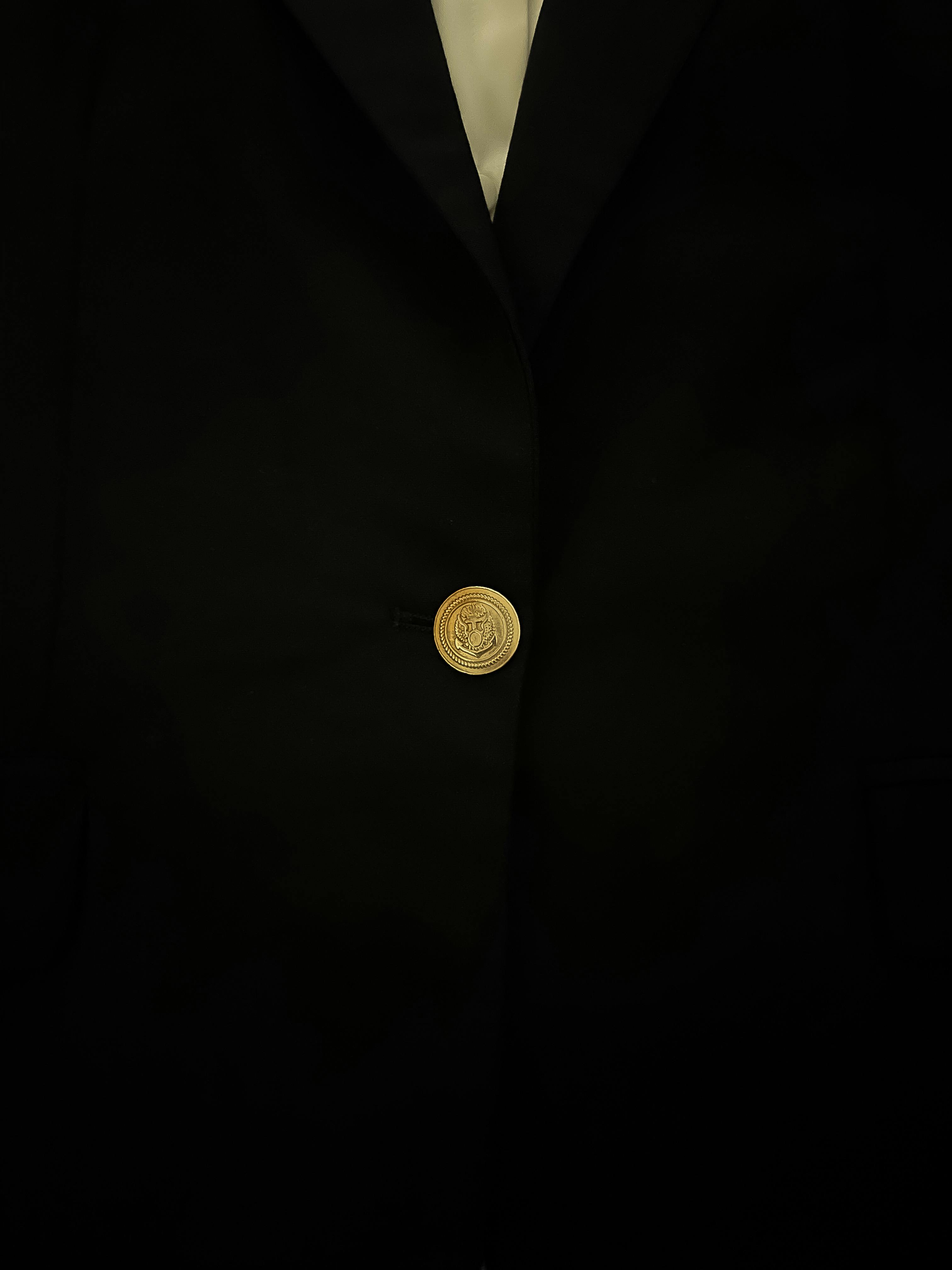 Gratis Primer plano de una elegante chaqueta de traje negra con un solo botón dorado en foco. Foto de stock