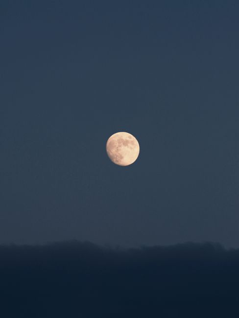 Beautiful full moon shining brightly in a clear night sky above the dark clouds.