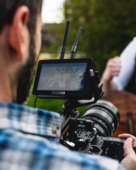 Close-up of a videographer using a camera rig with a monitor screen outdoors in London.