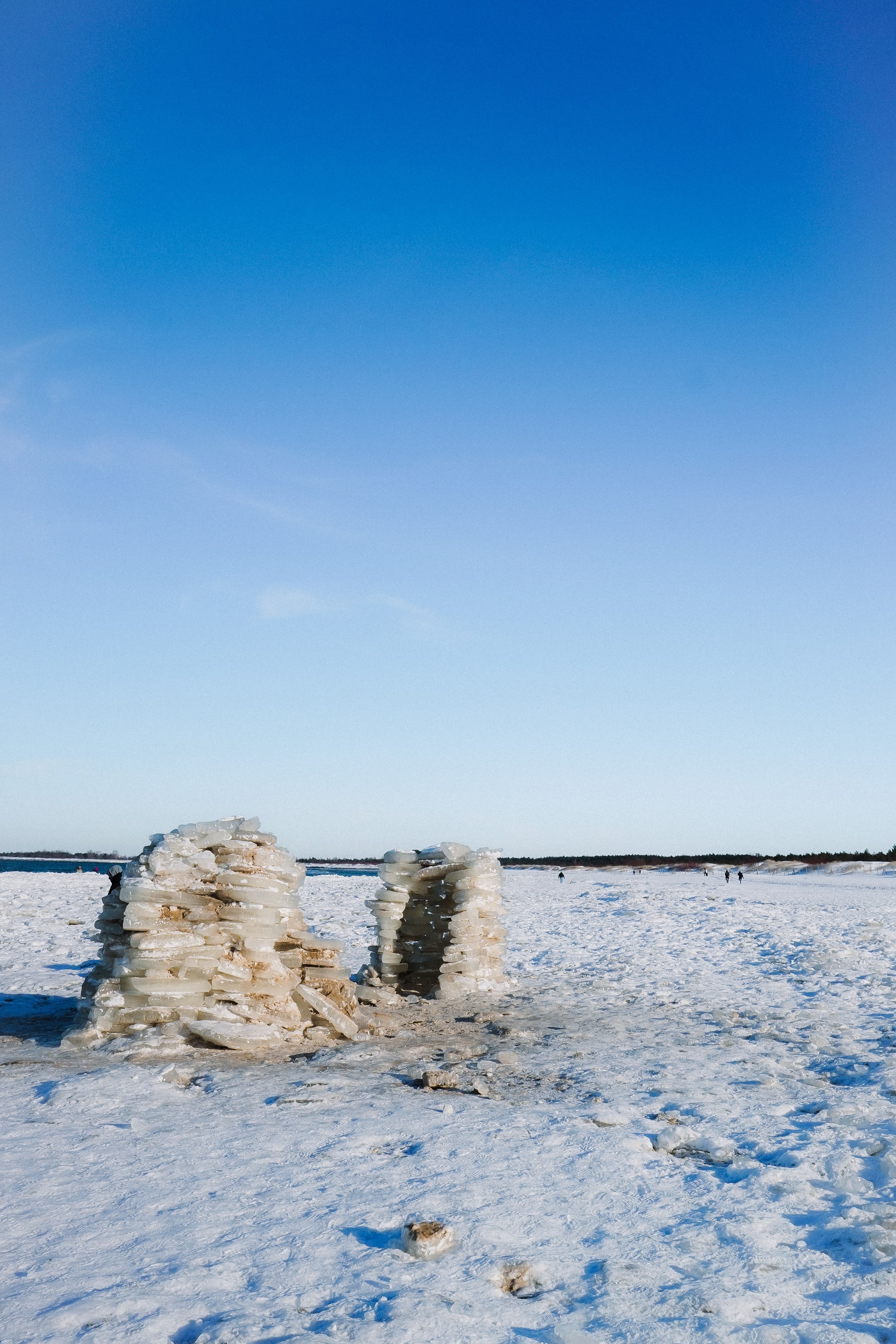 An ice sculpture stands on a vast snowy expanse under a clear blue sky, showcasing winter's beauty.