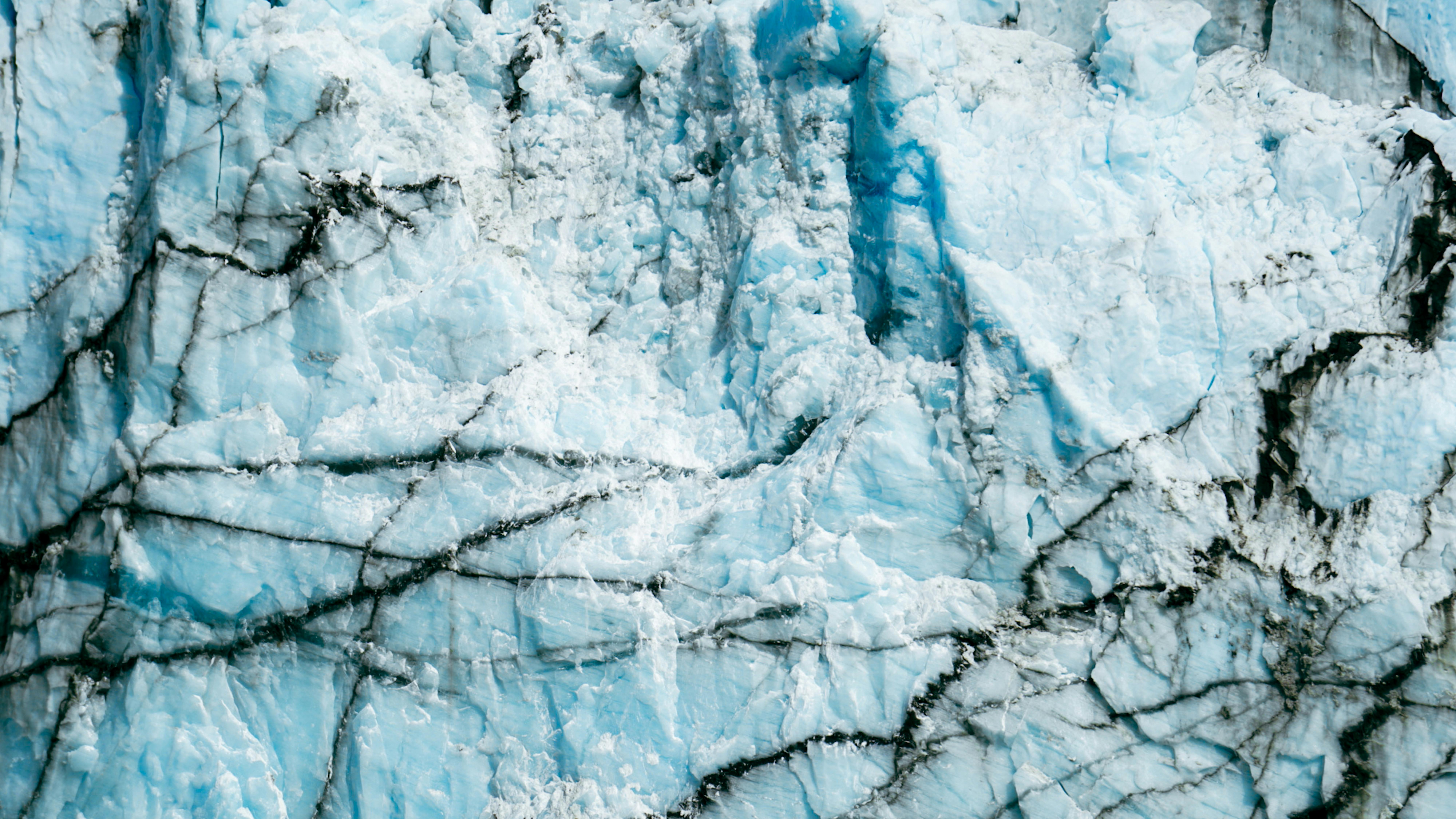 Detailed close-up of a glacier's textured ice surface with striking blue hues.