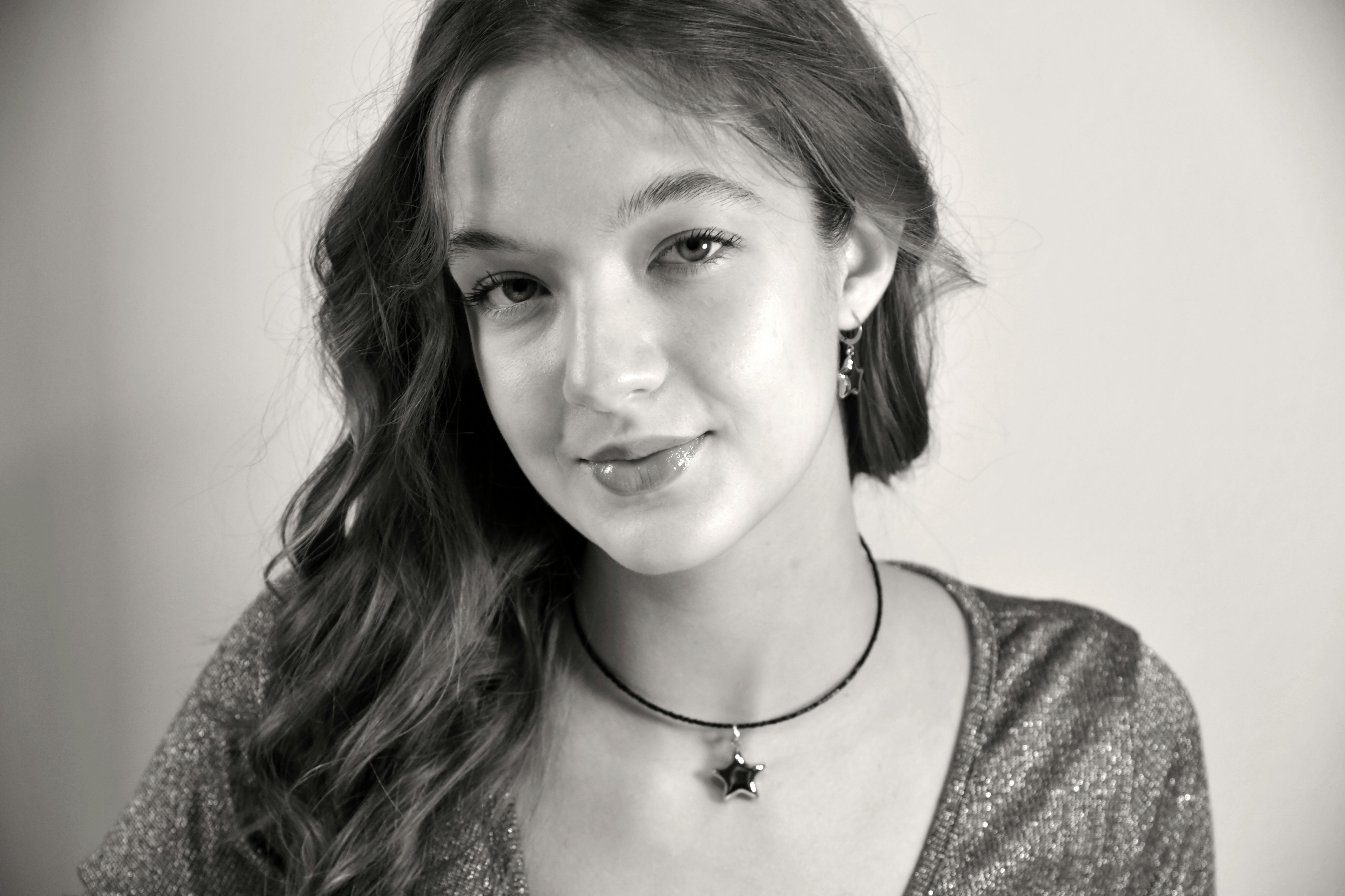 бесплатная Черно-белый портрет молодой женщины с длинными волосами, в колье со звездой. Стоковое фото
