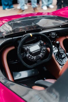 Interior view of a sleek sports car steering wheel and dashboard with futuristic design.