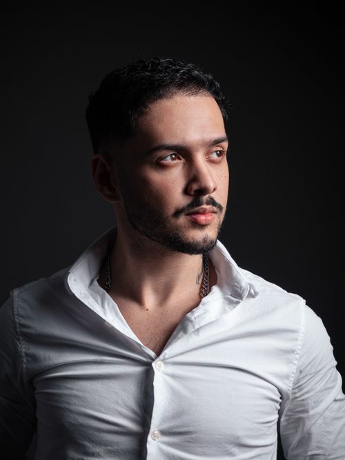 Free Stylish young man in a white shirt posing against a dark background. Stock Photo