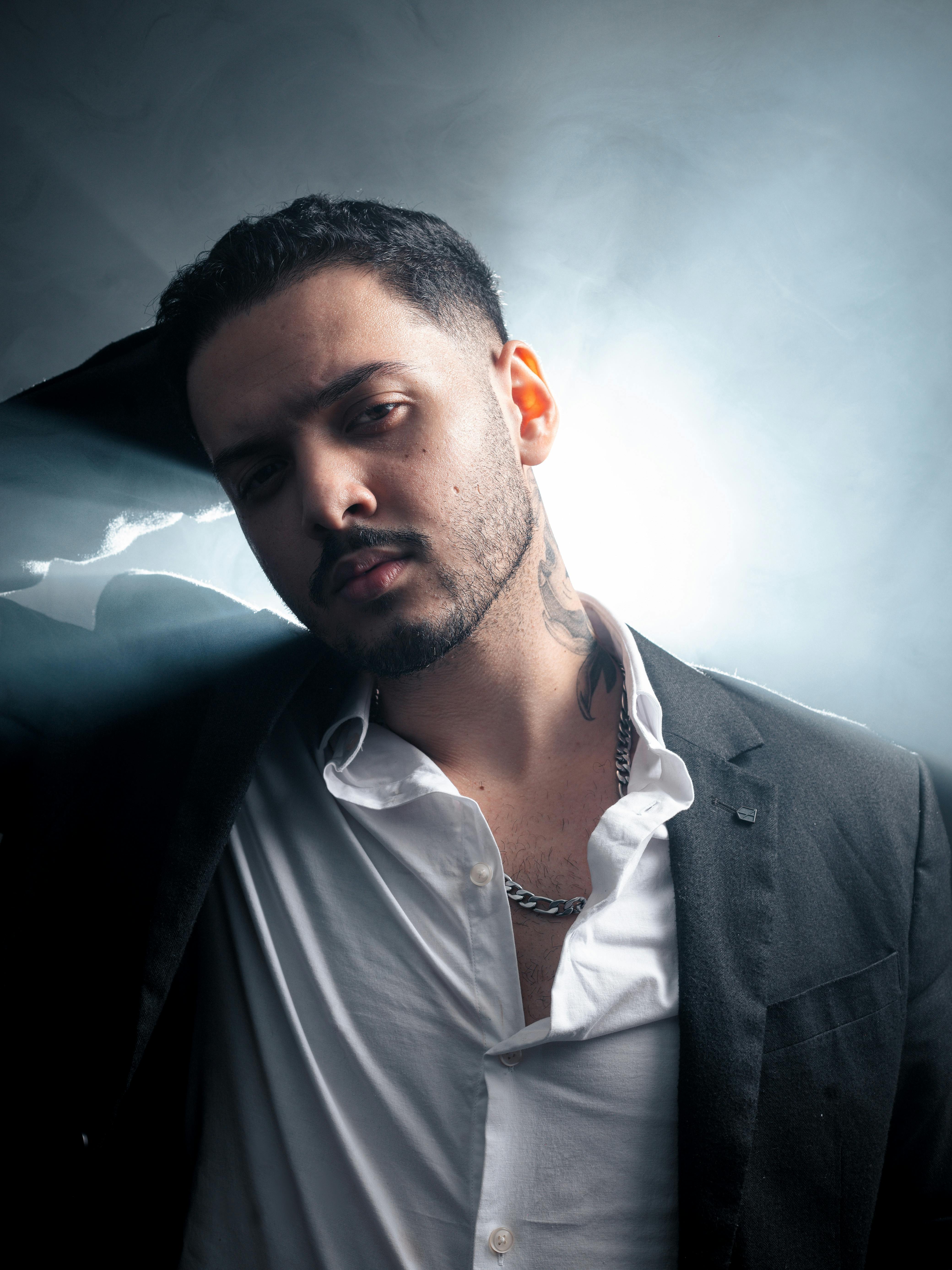 Stylish man posing in suit with moody smoke background, creating a dramatic ambiance.