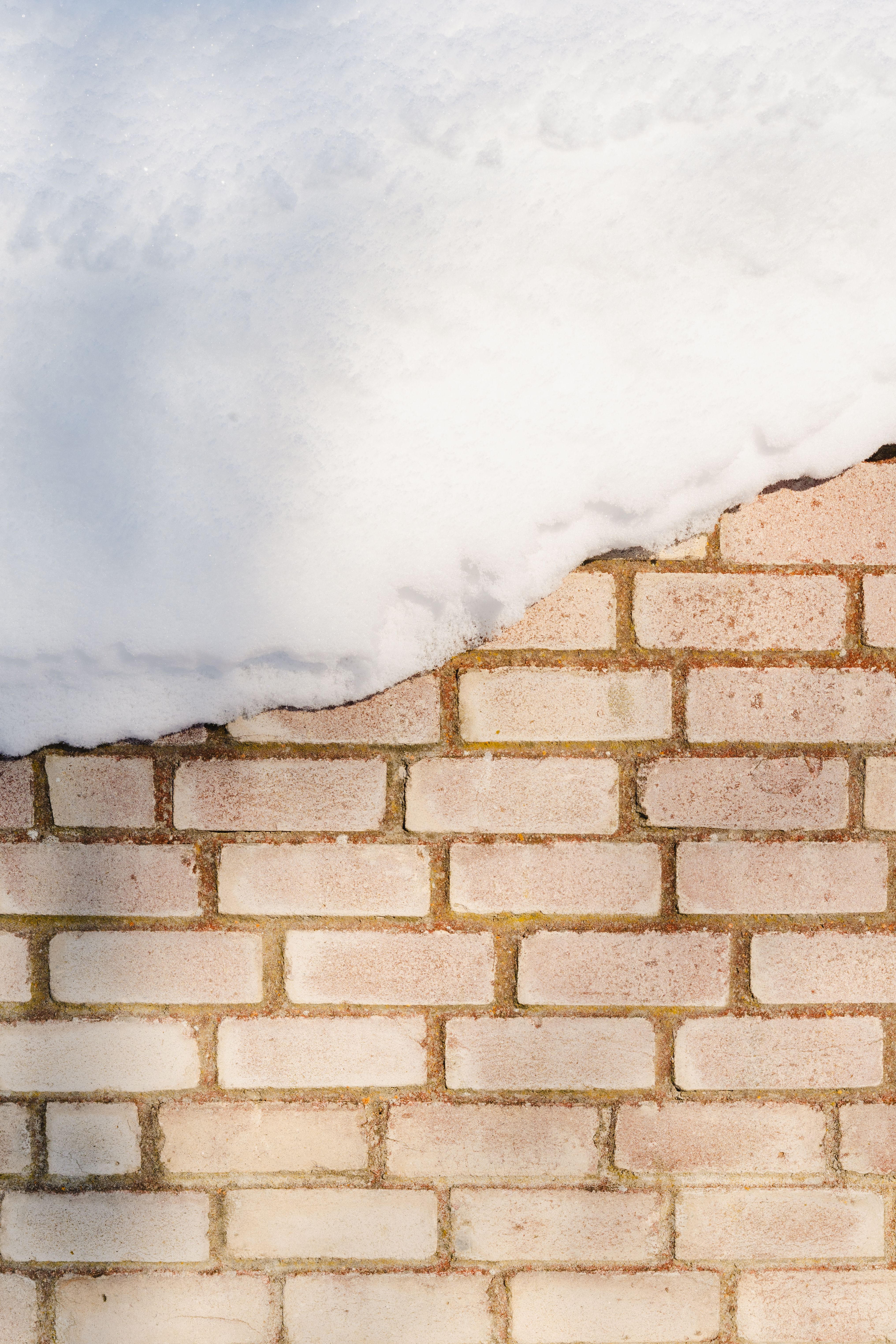 Snow-Covered Brick Wall in Winter Sunlight · Free Stock Photo