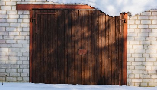Wooden garage door framed by brick walls in winter