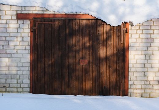 Wooden garage door framed by brick walls in winter