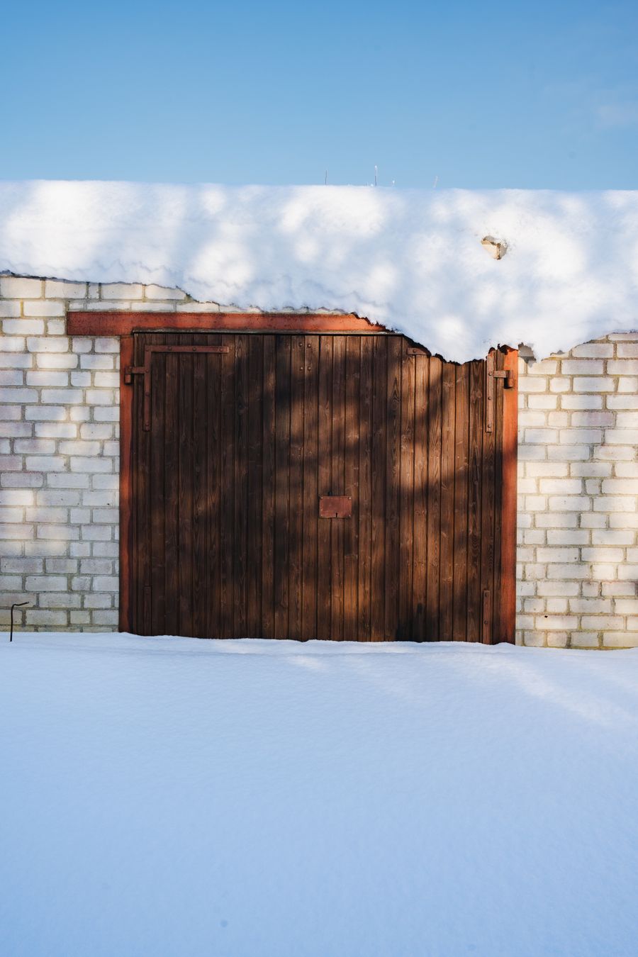 A wooden garage door framed by brick in winter