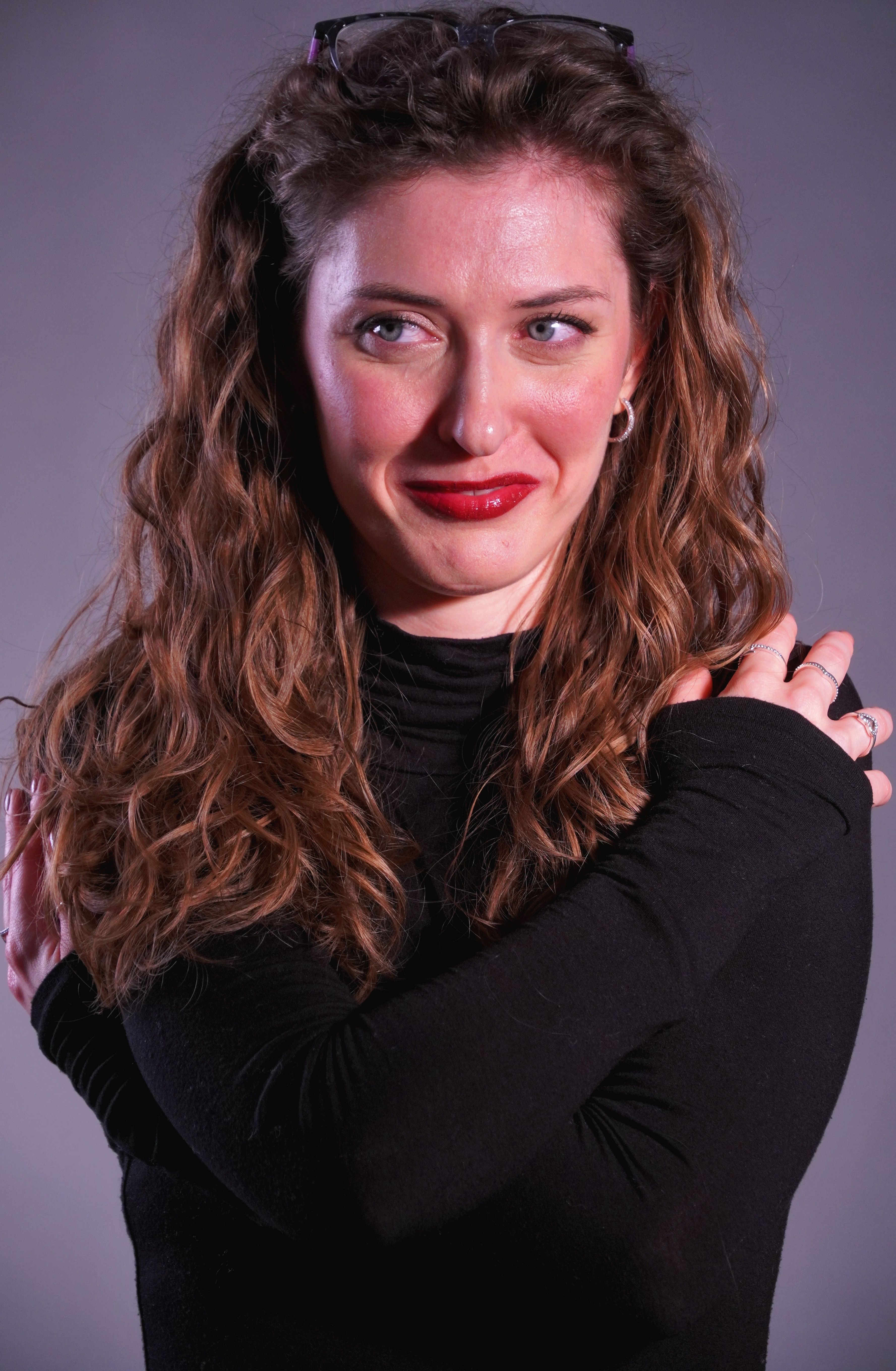 Portrait of a woman smiling in a studio setting wearing a black sweater.
