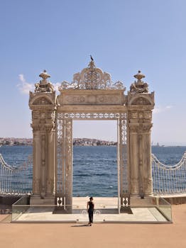 A scenic view of the ornate gate at Dolmabahçe Palace with the Bosphorus in the background.