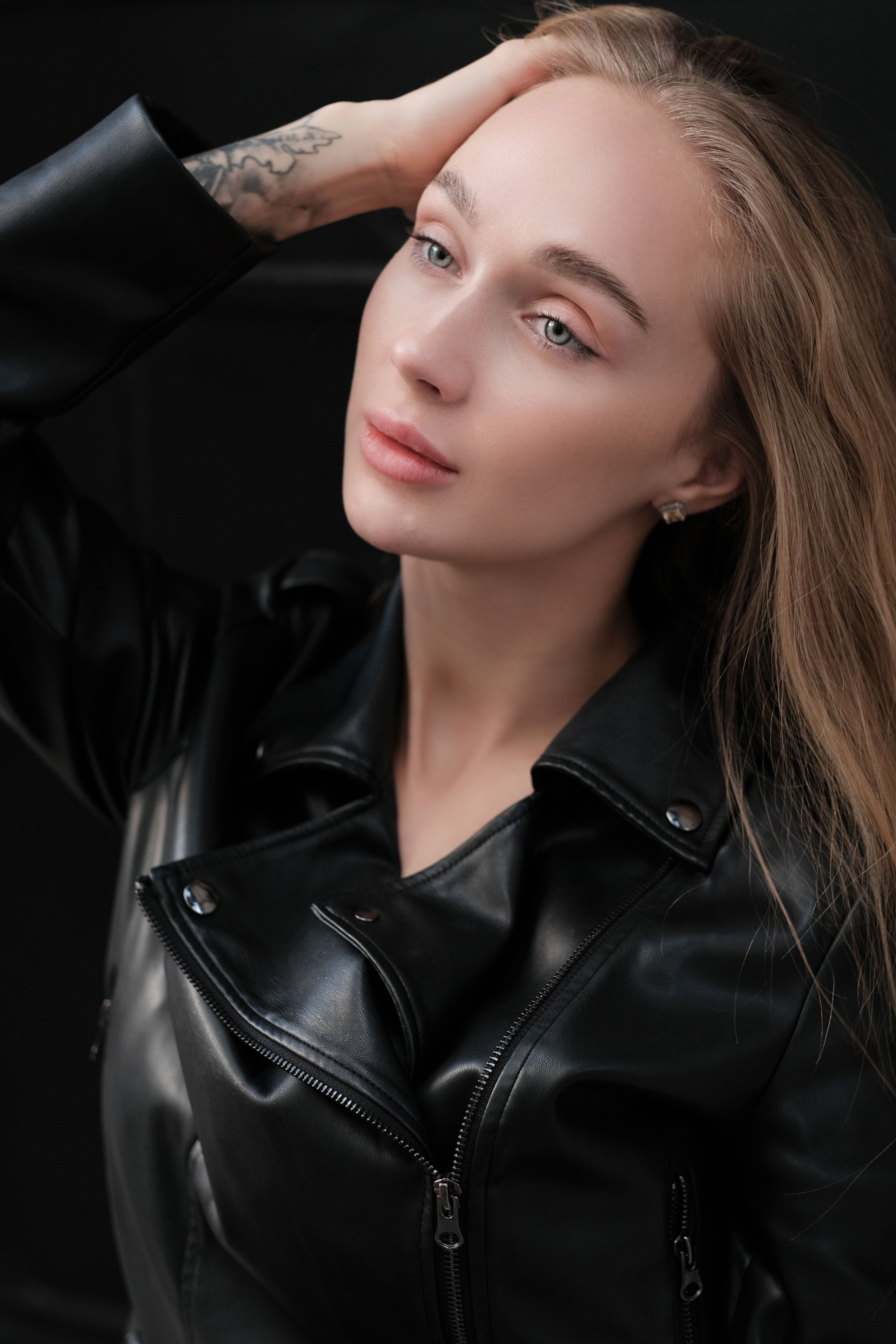 Sophisticated portrait of a woman in a black leather jacket, indoors.