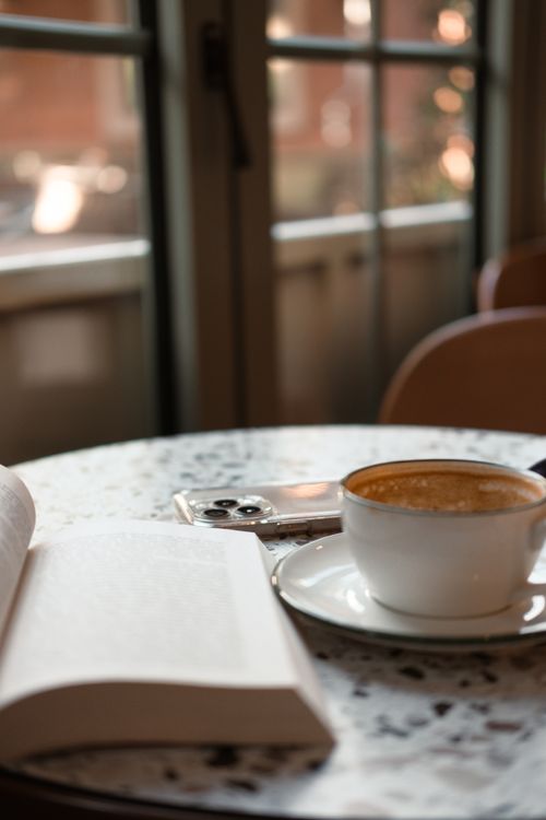 Free Warm coffee break scene in an İstanbul cafe, featuring a cup, book, and smartphone. Stock Photo