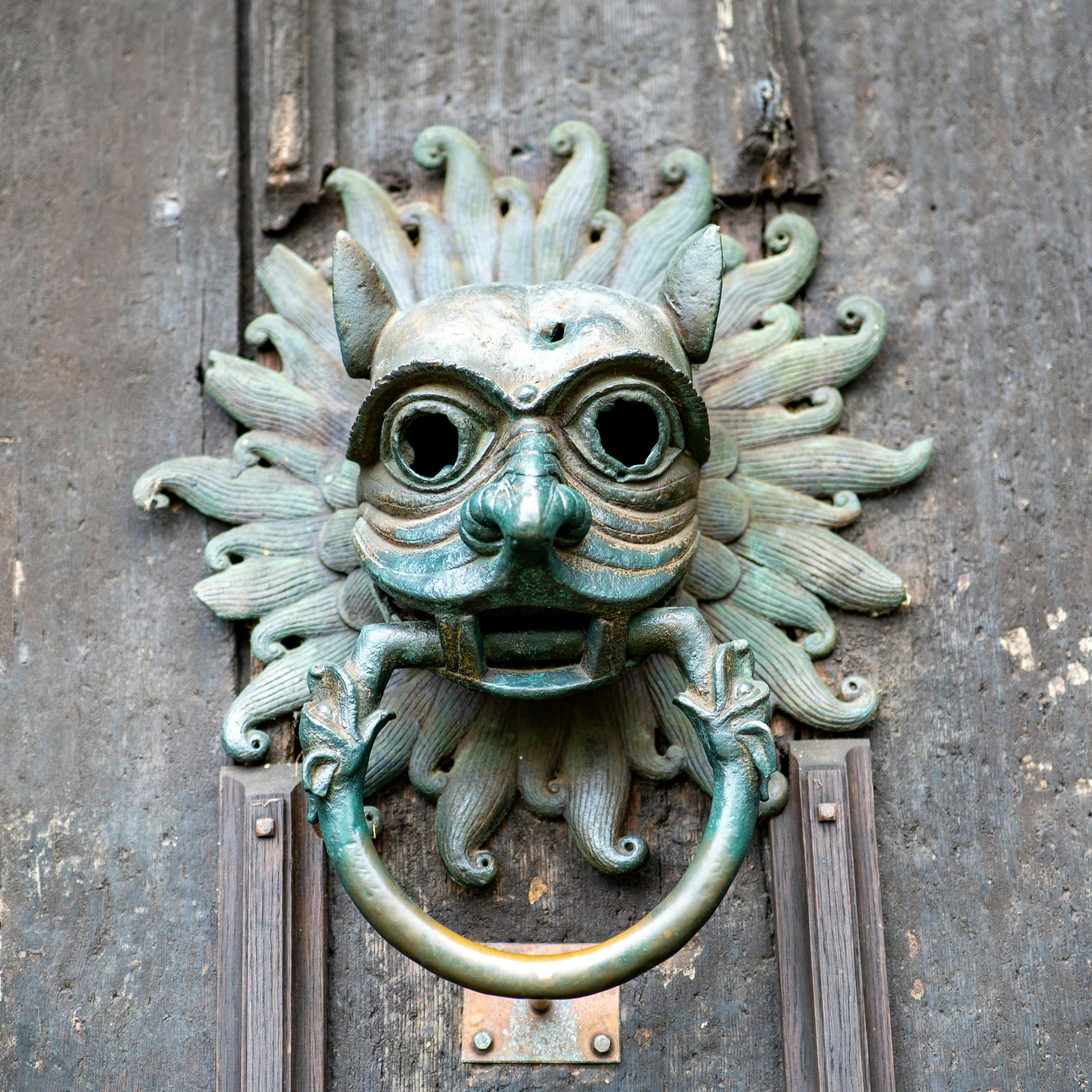 Close-up of a lion head door knocker with ornate design on a historic wooden door in England.