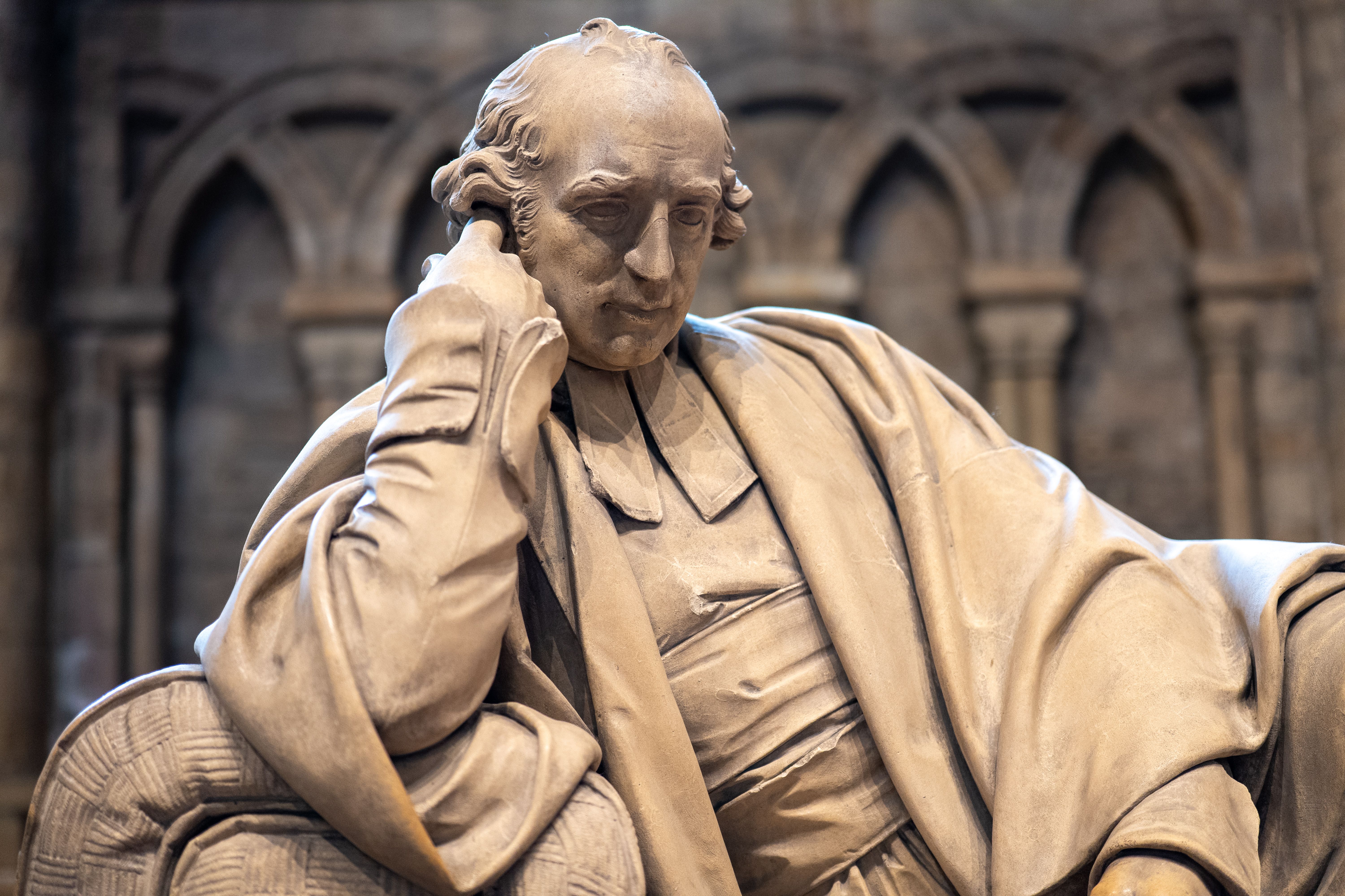 Elegant stone statue depicting a thoughtful figure in a historic setting.
