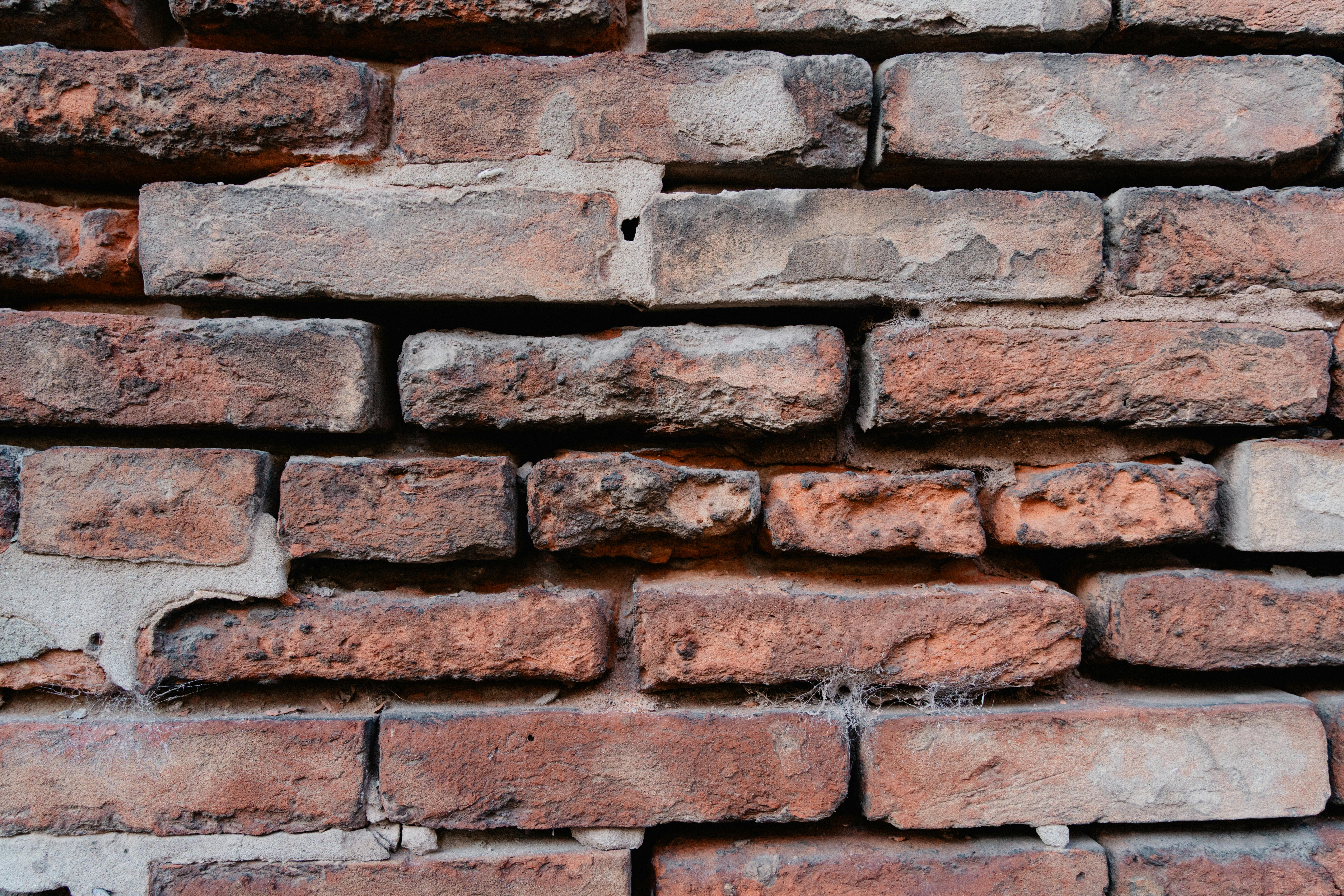 бесплатная Детальный крупный план старой кирпичной стены из красного кирпича, демонстрирующий текстуру и деревенский вид. Стоковое фото