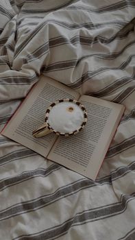 A warm, inviting scene of a coffee cup on an open book, set atop a striped bedsheet.