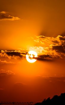 A stunning sunset with vibrant orange sky and clouds obscuring the sun, captured outdoors.