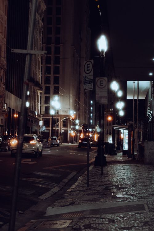 Free A moody nighttime city street scene from São Paulo with cars and illuminated lampposts. Stock Photo