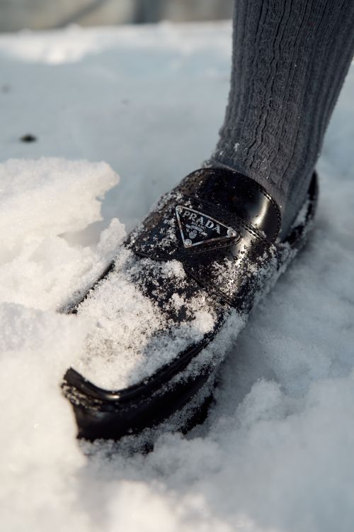 Free A luxury black loafer partially covered in snow, providing a contrast against the white backdrop. Stock Photo