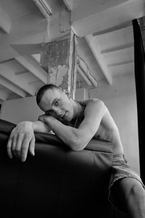 Free Artistic black and white portrait of a young man resting on a couch. Stock Photo