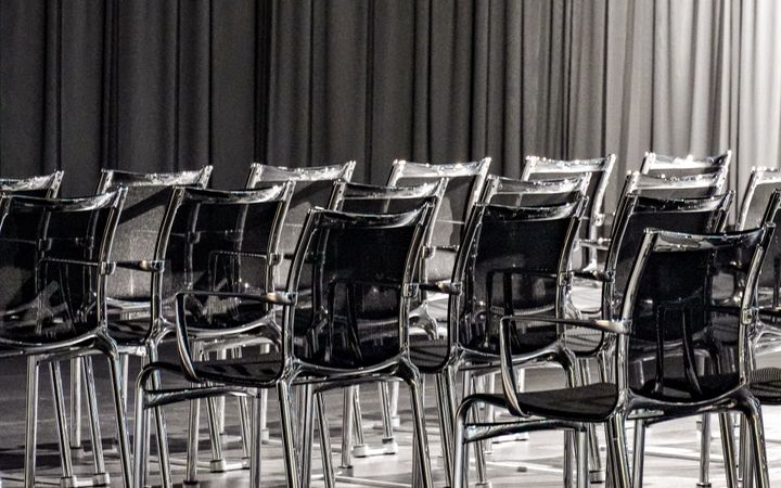 Rows of empty transparent chairs in a modern conference room, creating a minimalist aesthetic.