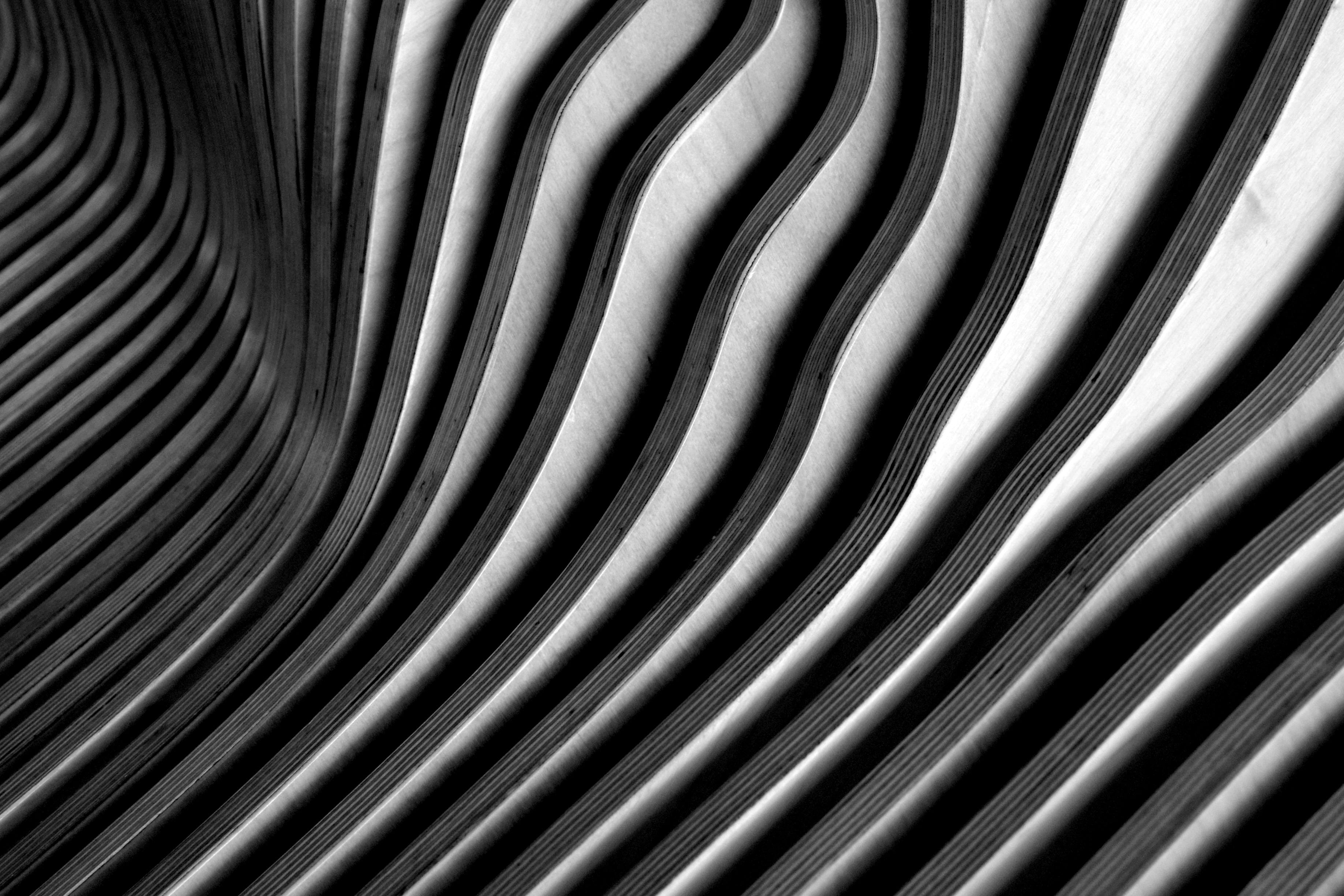 Gratuit Des lattes de bois incurvées créent un motif abstrait ondulé avec un contraste saisissant d'ombre et de lumière. Photos