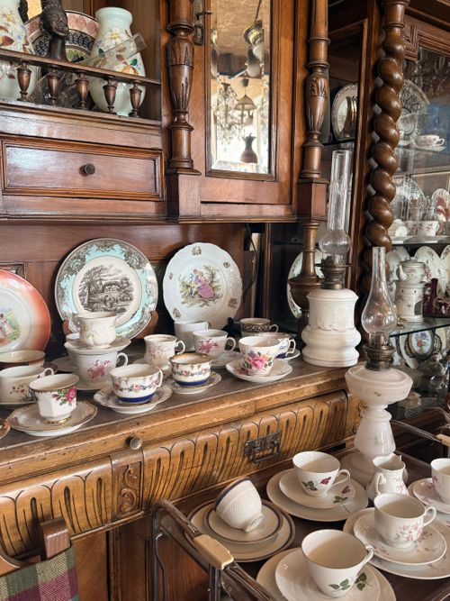 Free A vintage tea set with floral designs displayed in an antique wooden cabinet. Stock Photo