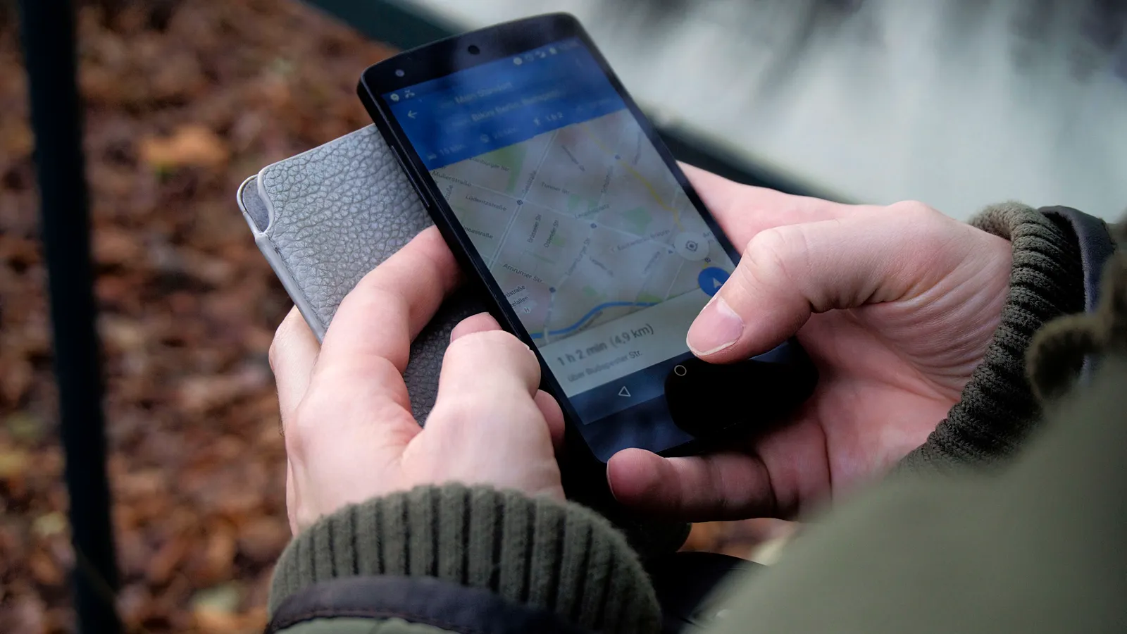Person holding phone showing a map search near a cafe street