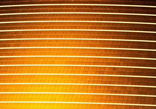 A luminous golden architectural facade with horizontal lines creating an abstract pattern.