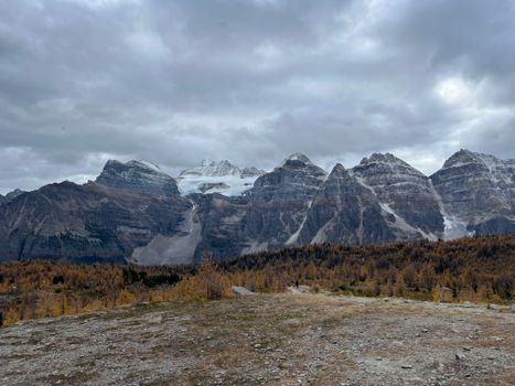 A stunning view of a rugged mountain range with autumn foliage under an overcast sky.