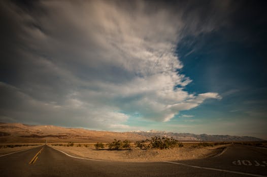 Empty desert road under a dramatic sky in a remote landscape setting.