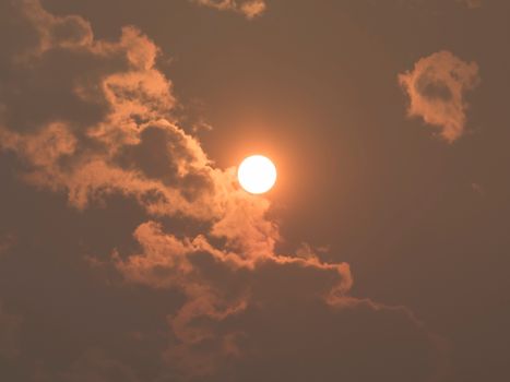 A vibrant sunset with the sun shining through dramatic clouds creating a warm glow.