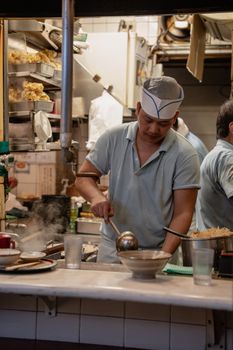 A chef prepares food in a Shinjuku izakaya, Tokyo, showcasing traditional Japanese cuisine.