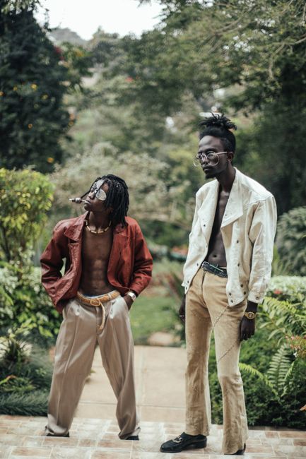 Two stylish black men posing confidently outdoors in trendy outfits.