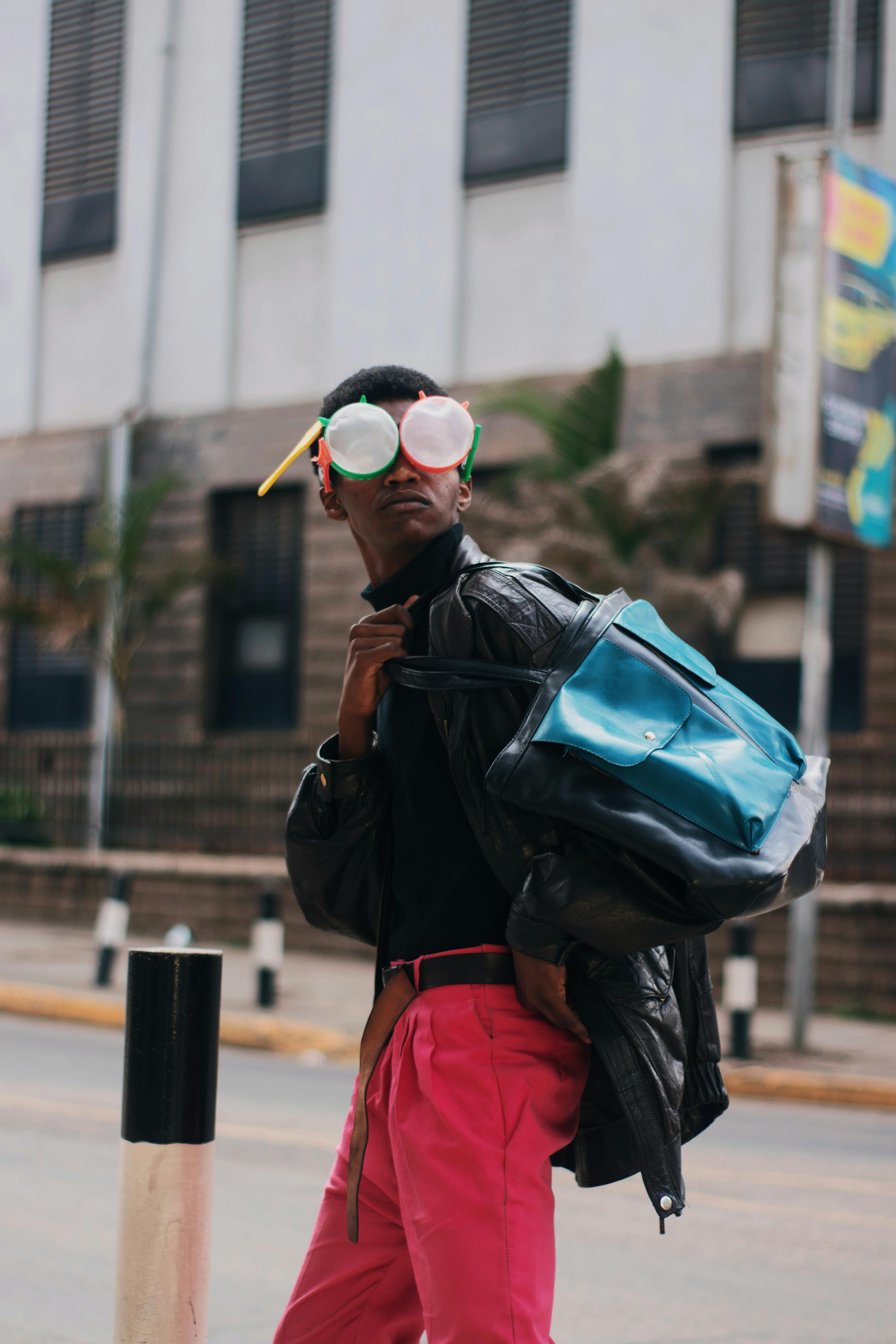 一名时尚男子在城市中穿着黑色皮夹克，戴着彩色眼镜