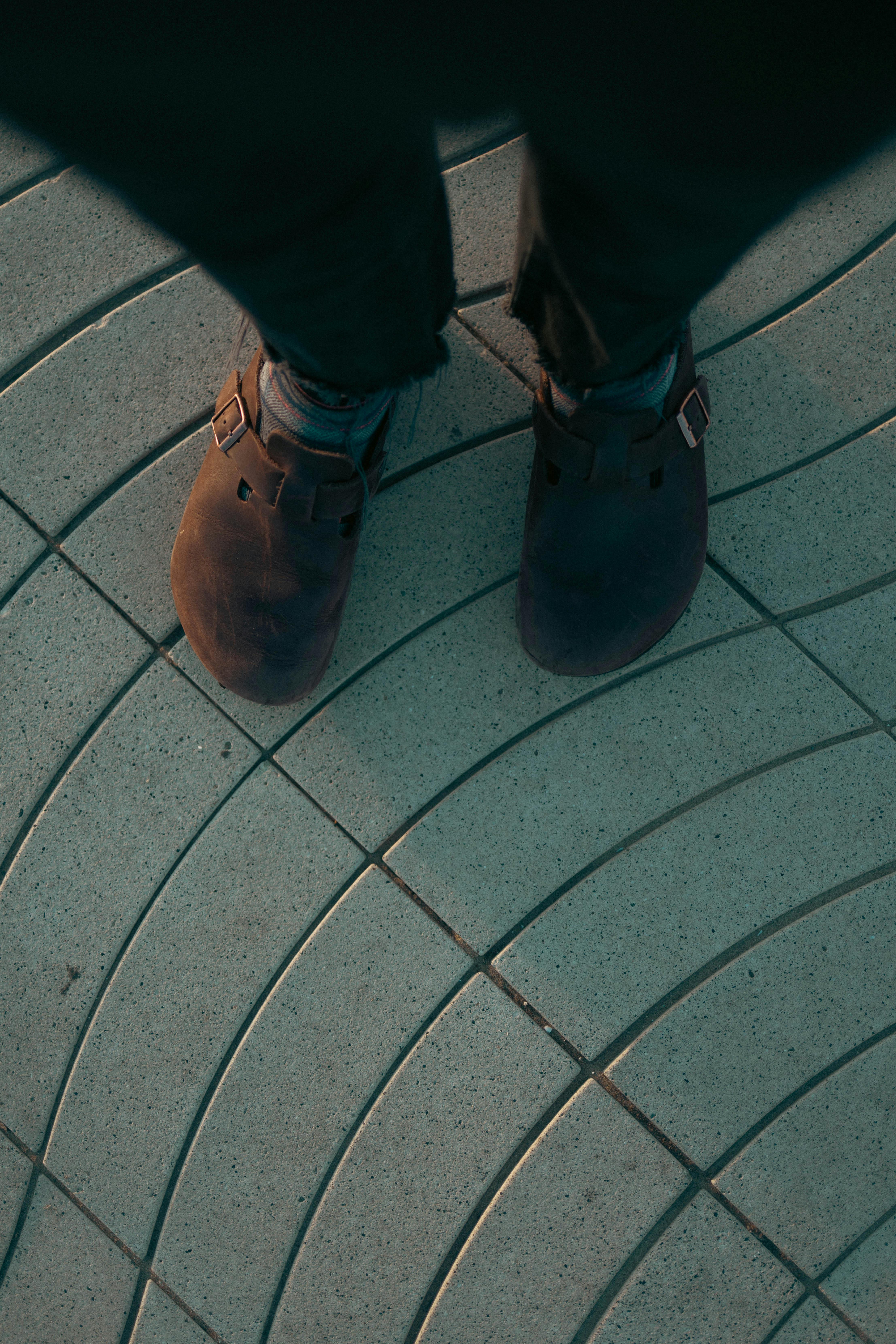 Gratis Vista dall'alto di scarpe casual su un marciapiede circolare decorativo. Foto a disposizione