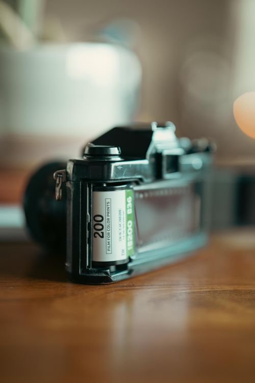 Free Vintage film camera with Kodak 200 film roll on a wooden table. Stock Photo
