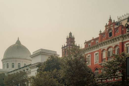 Colonial-era buildings in Kolkata showcasing iconic architectural styles under a warm hazy sky.