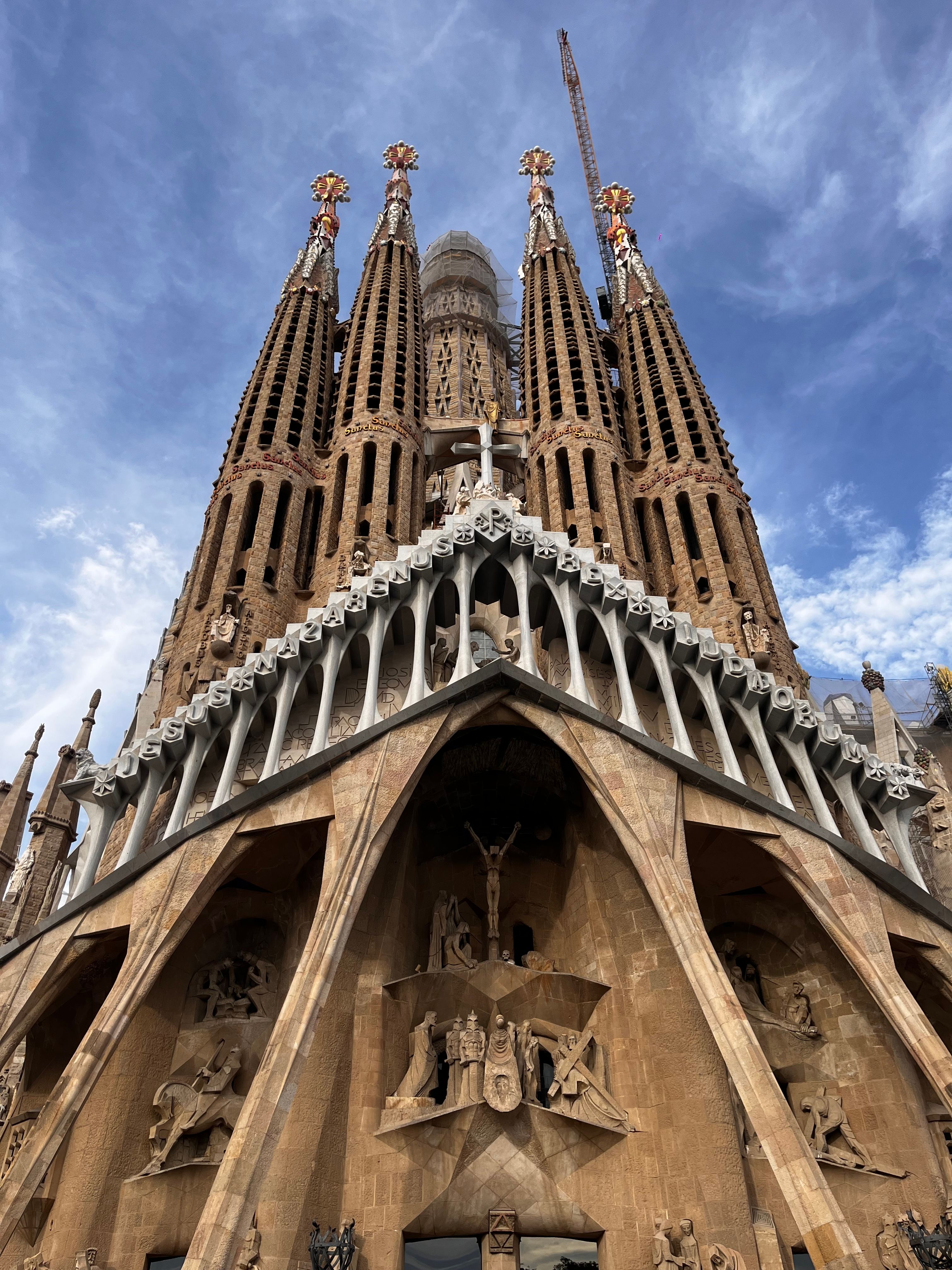 Iconic view of Sagrada Familia in Barcelona, showcasing historic architecture under a bright blue sky.