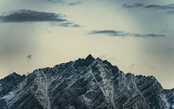 Dramatic snow-covered mountain peaks under a moody, cloudy sky.