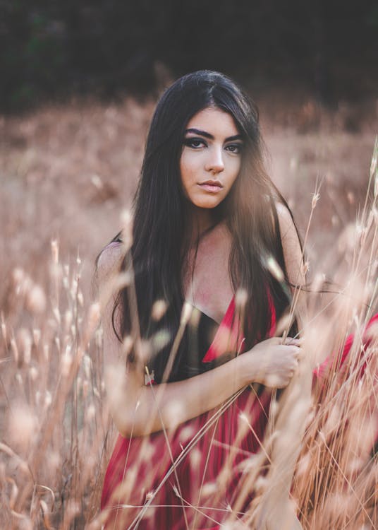 Woman In Red And Black Dress Standing On Brown Grass Field