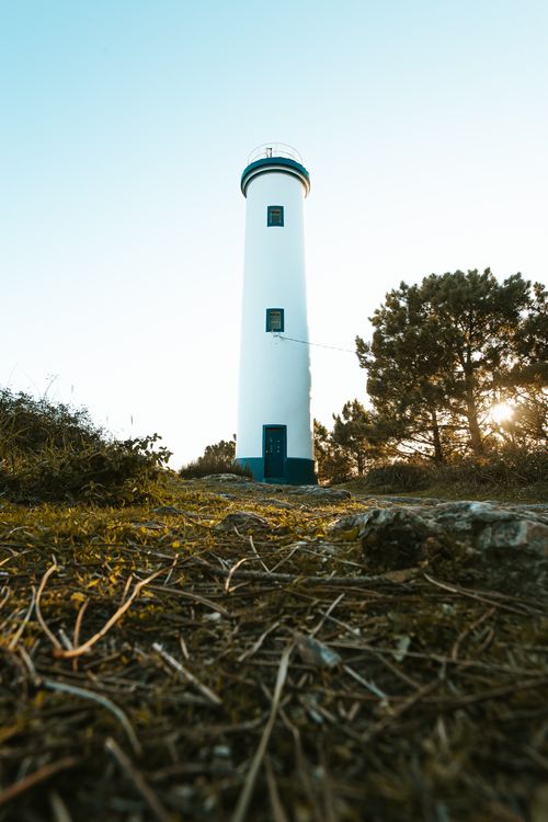 Free Lighthouse standing tall at sunrise with natural surroundings, showcasing tranquility. Stock Photo