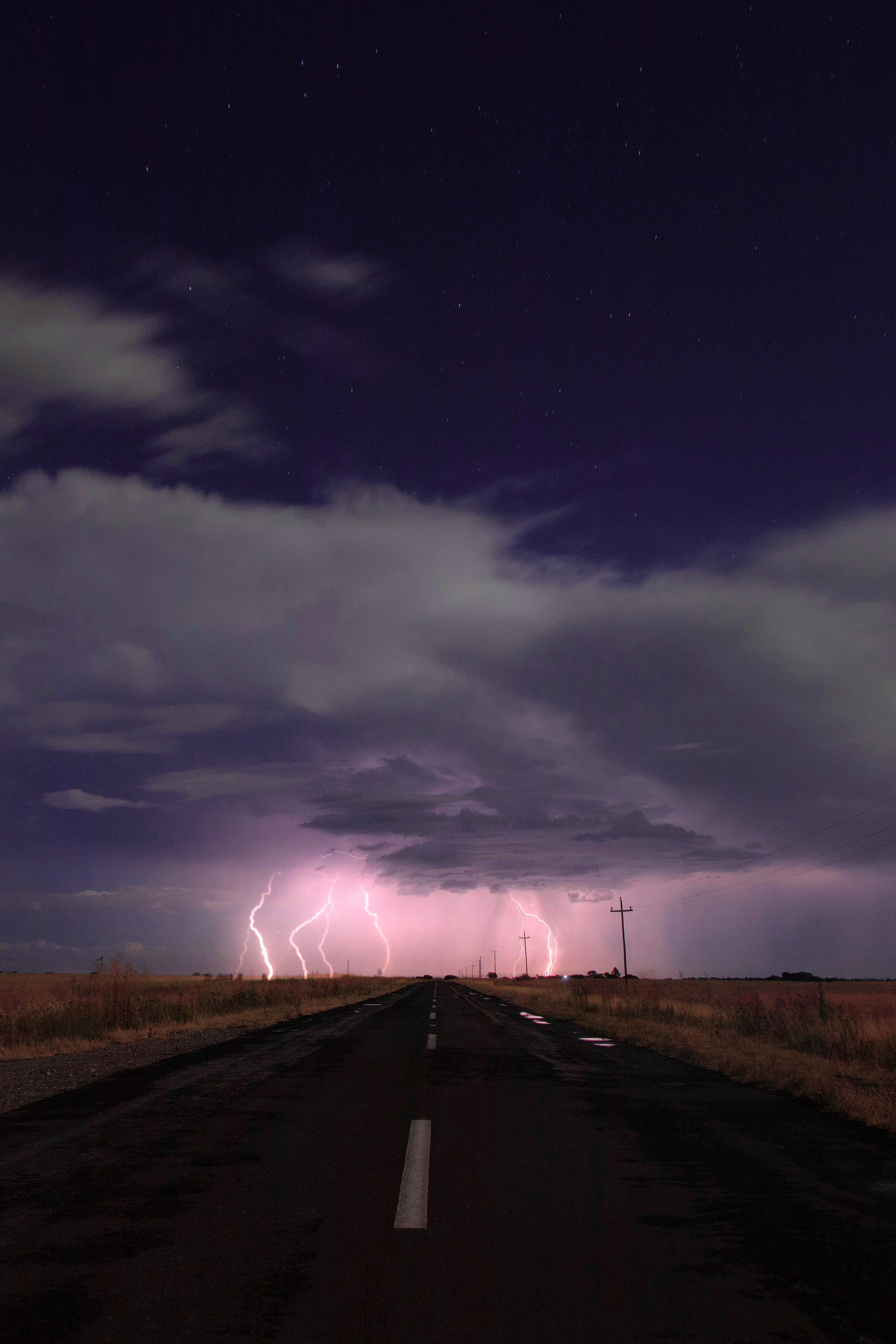 A striking scene of a lightning storm illuminating a deserted road and night sky.