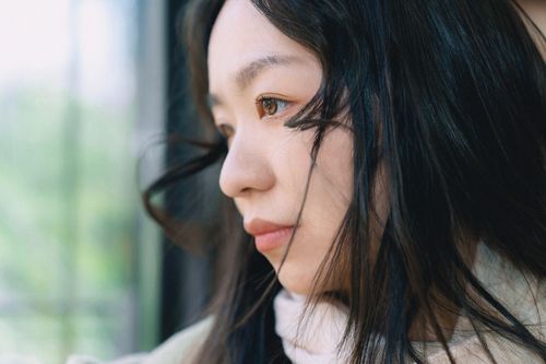 Free Close-up portrait of a young woman gazing outside, lost in thought. Stock Photo